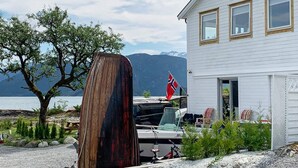 A white house with a dock, a boat, and a flag. - 5 Person Holiday Home in Torrvikbygd (Kvam)