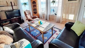 Een gezellige woonkamer met een televisie, leren banken, een salontafel en een boekenkast.