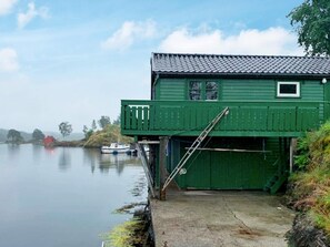 A green building with a dock extending into calm water, a ladder, and a small window. - 6 Person Holiday Home in Lindas (Alver)