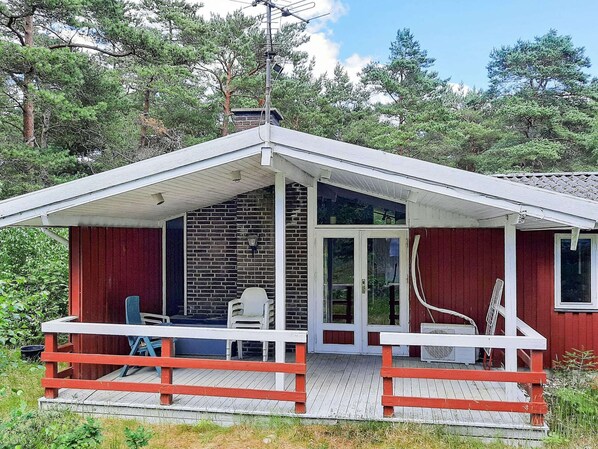 Eine Hütte mit Veranda, einer Ziegelwand und einer Holzterrasse.