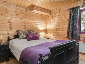 A wooden-paneled bedroom with a bed, pillows, a nightstand, a lamp, and a window with curtains. - Holiday Home in Tonstad (Sirdal)