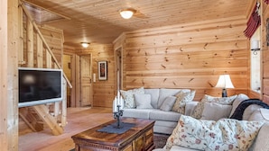 A cozy living room with wooden walls, a sofa set, a coffee table, and a flat-screen TV. - Holiday Home in Tonstad (Sirdal)