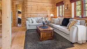 A cozy log cabin interior with two sofas, a wooden coffee table, and a fireplace. - Holiday Home in Tonstad (Sirdal)