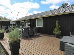 A covered outdoor area with a wooden deck, outdoor furniture, and potted plants. - Holiday Home in Hemmet (Hemmet)