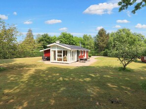 Une maison de plain-pied à l’extérieur rouge, dotée d’un patio couvert.
