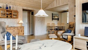 A spacious living area with a marble table, wooden furniture, and a dining set.