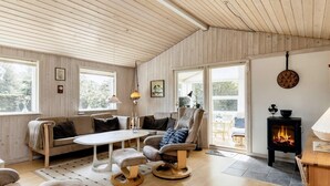 A cozy living room with wooden floors, a sofa, a chair, a table, and a fireplace.