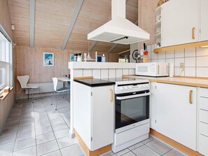 A modern kitchen with white cabinetry, a built-in oven, a microwave, and a wooden ceiling.