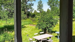 Eine Holzterrasse mit Tisch und Stühlen, umgeben von üppiger Vegetation und Bäumen.