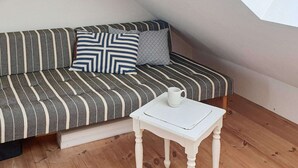A room with a striped sofa, a small white table, and a white mug. - Holiday Home in Snedsted (Snedsted)