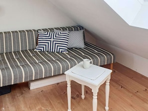Una habitación con un sofá a rayas, una mesita blanca y una taza blanca.