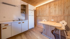 Een keuken met witte kasten, een houten aanrechtblad en een vastgezet houten wandpaneel.