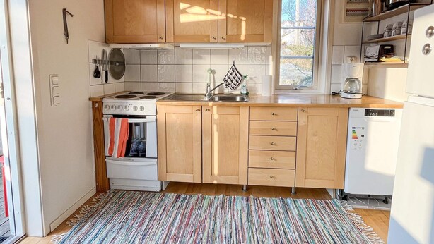 A compact kitchen with wooden cabinets, a stove, a sink, and a dishwasher. - 4 Person Holiday Home in Fotö, Västra Götaland (Fotö)