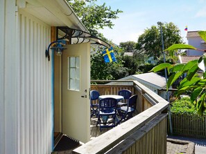 Eine Holzdielen-Terrasse mit einer Tür, einer Flagge und Gartenmöbeln.