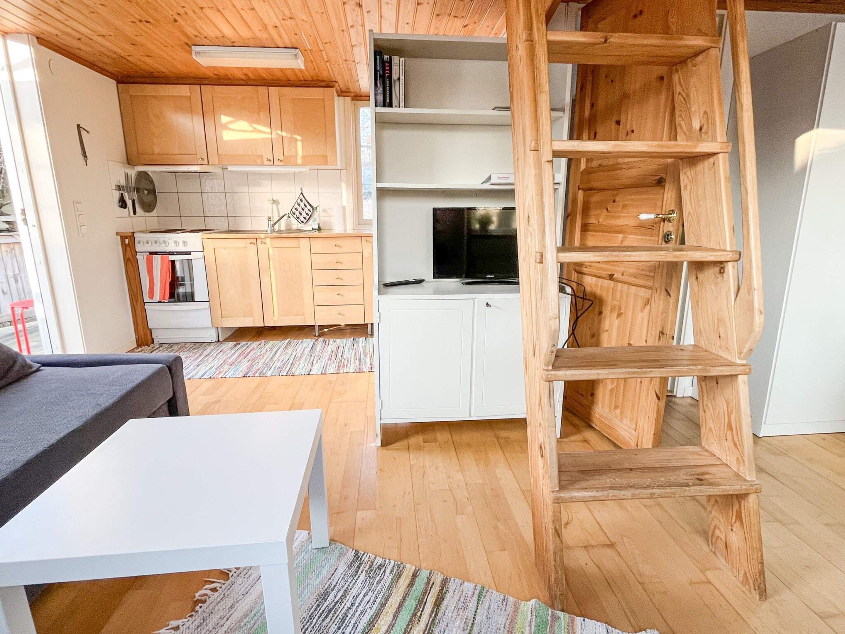 A compact kitchen with wooden cabinets, a white countertop, and a built-in TV.