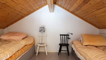 Un dormitorio ático pequeño con dos camas, una silla y una lámpara.