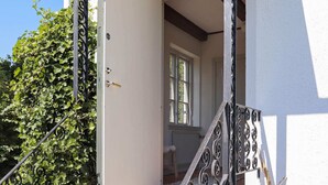 A white door with a brass handle, a metal staircase with decorative balusters, and a green ivy-covered wall. - Holiday Home in LÃ¶derup (Loderup)