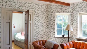 A cozy room with a bed, a brown leather armchair, a wooden table, and a window with a view of trees. - Holiday Home in LÃ¶derup (Loderup)