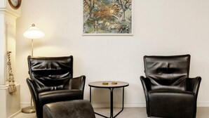 A room with two black leather chairs, a small round table, a floor lamp, and a painting on the wall. - 6 Person Holiday Home in Aeroskobing (Aeroskobing)