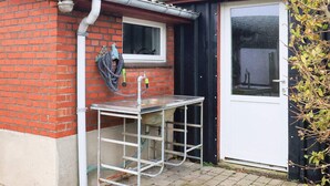 A small outdoor kitchen area with a metal table and a window above it. - 6 Person Holiday Home in Aeroskobing (Aeroskobing)