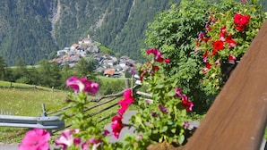 Ein malerischer Blick auf ein Dorf mit Häusern, einer Kirche und Bergen im Hintergrund.