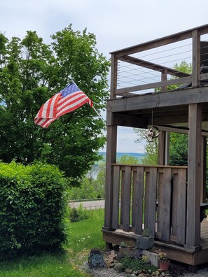 A wooden structure with a balcony, surrounded by greenery and an American flag.