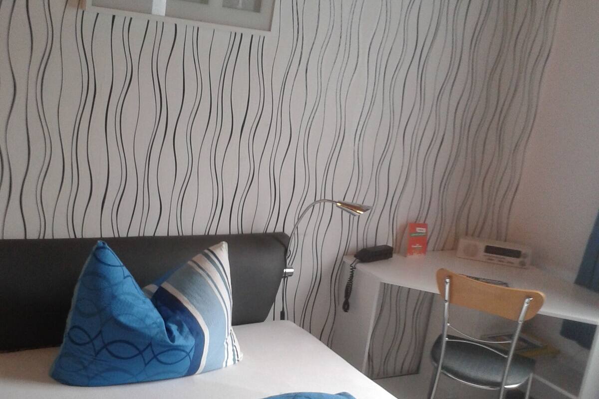 A hotel room with a bed, a desk, and a chair.