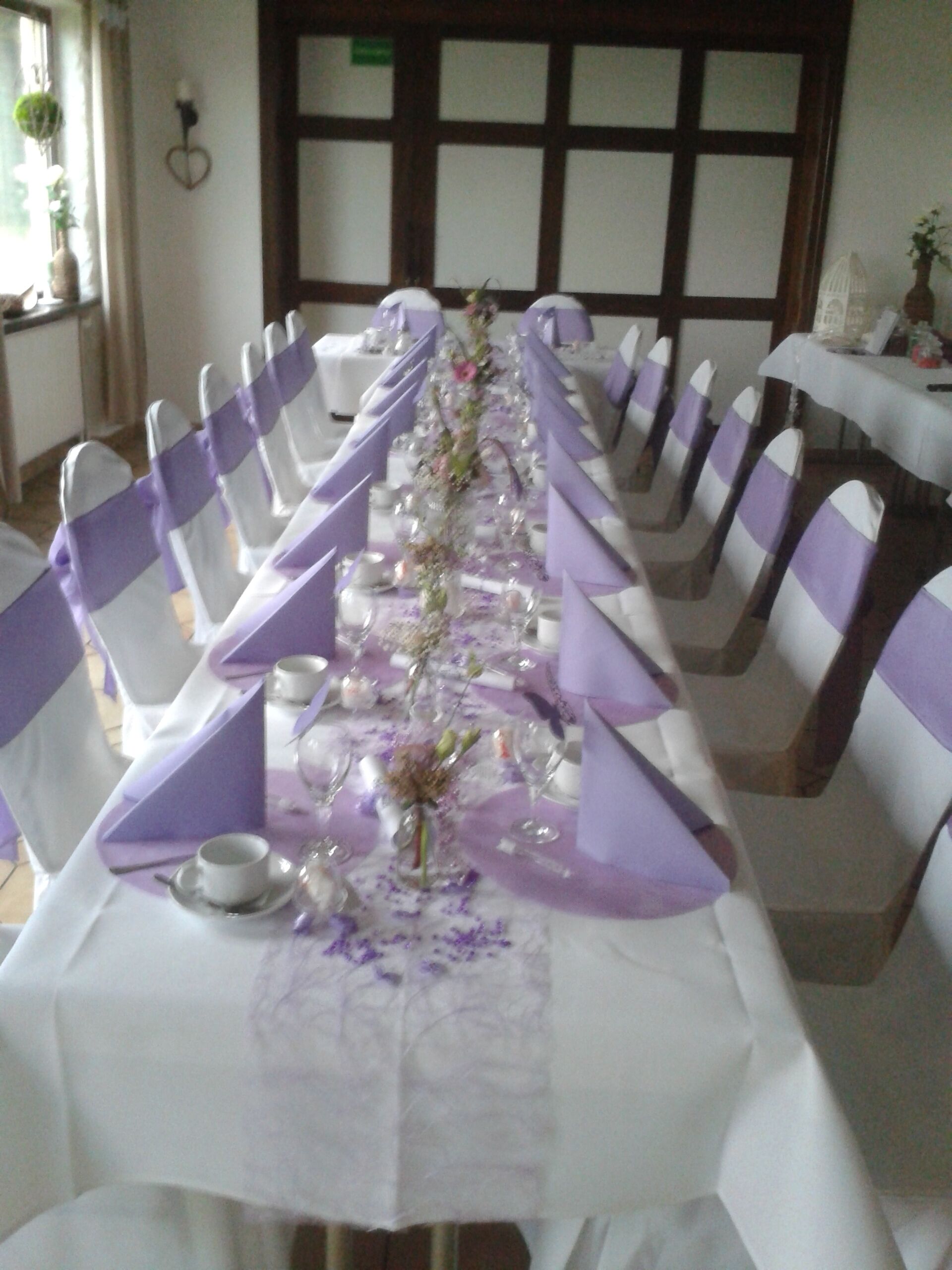 A long table with white chairs and purple sashes, set up for a formal event.