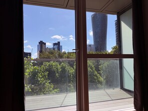 A balcony with a view of a cityscape, including a tall cylindrical building and several other high-rise buildings. - Charles Hope Apartment Canary Wharf (London)
