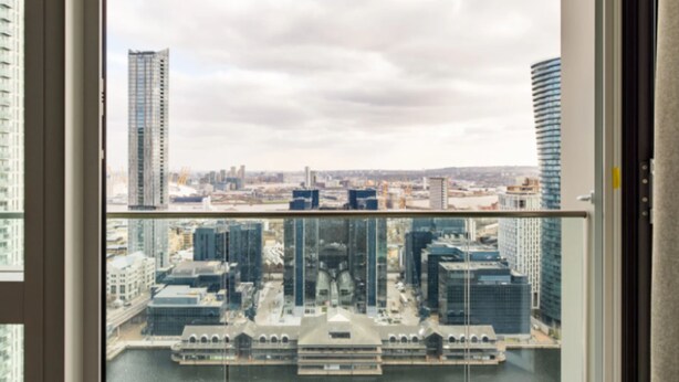 A view from a high-rise building with a river in the foreground and a cityscape in the background. - Charles Hope Apartment Canary Wharf (London)