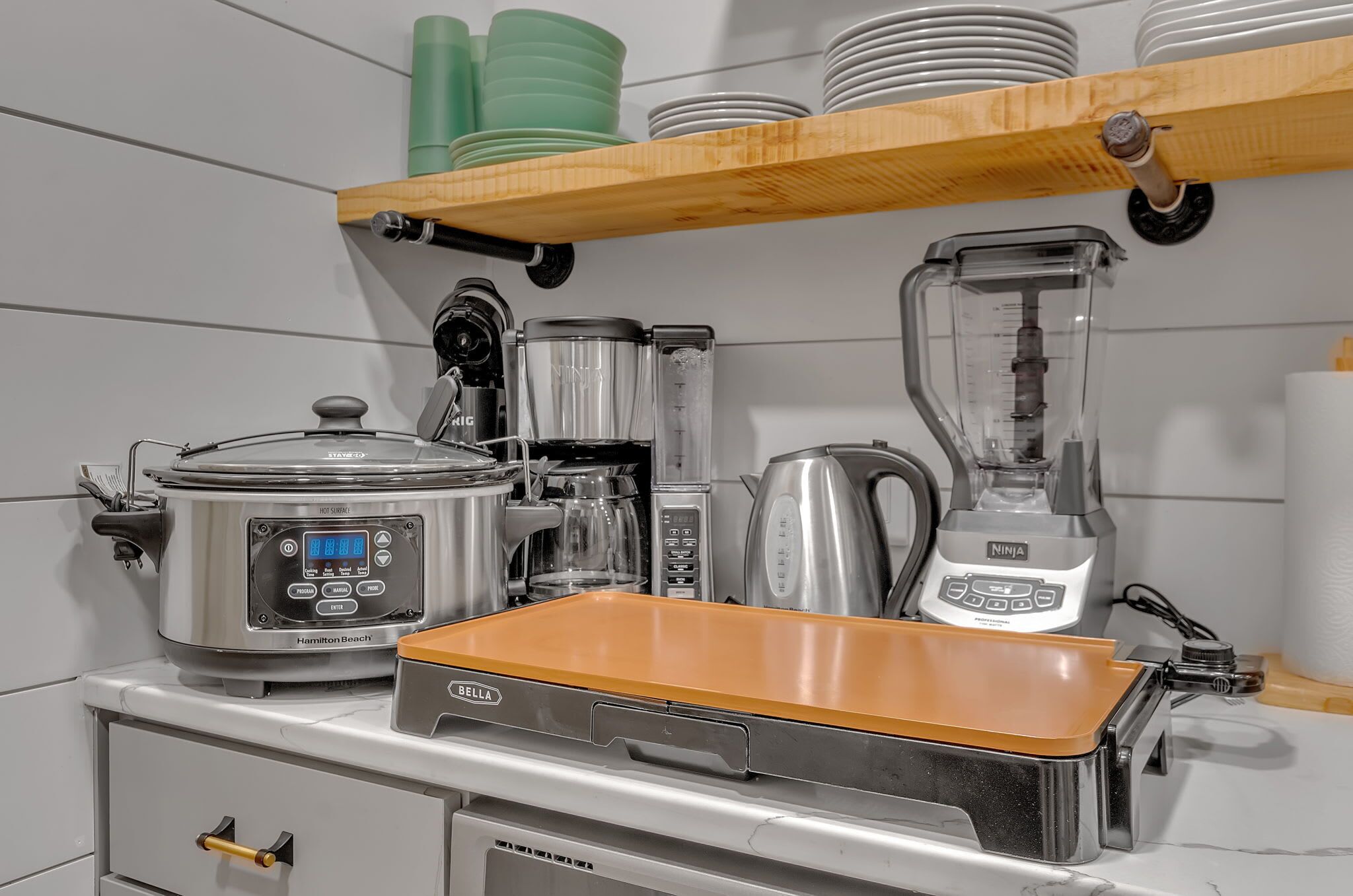 Une cuisine équipée d’une mijoteuse de la marque Hamilton Beach, d’un mixeur, d’une machine à café et d’une bouilloire.