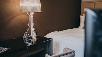Une chambre d’hôtel avec un lit, un bureau doté d’une lampe et une chaise.