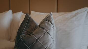 Una cama con almohadas blancas y una almohada acolchada oscura.