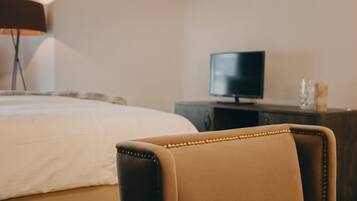 Una habitación de hotel con una cama, un televisor sobre un pedestal y una silla.