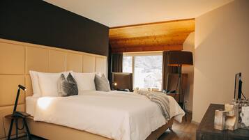 Un dormitorio con una cama grande, una lámpara de noche, una silla y una ventana con cortinas.