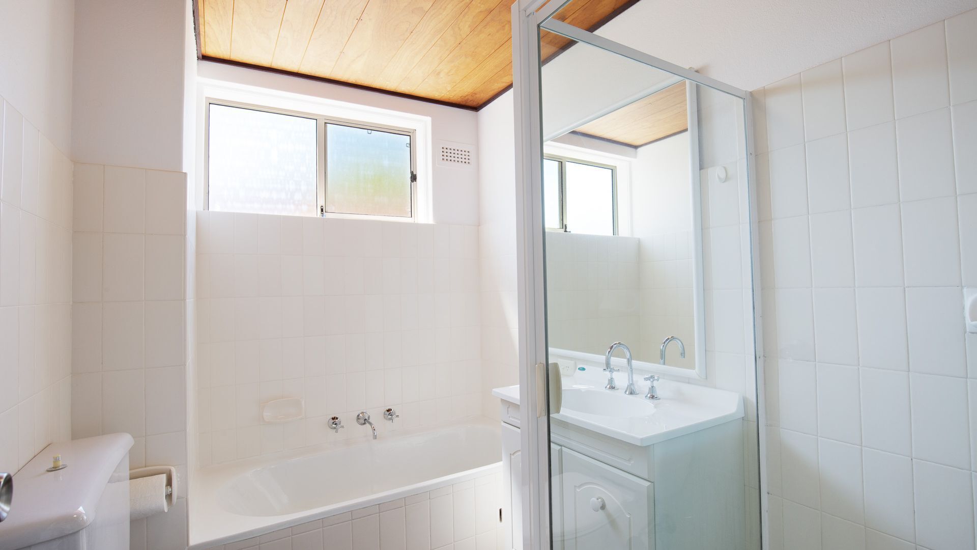 A modern bathroom with a bathtub, a shower, and a sink. There is a window above the bathtub and a mirror above the sink.