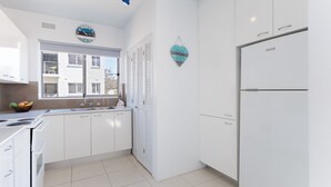 A modern kitchen with white cabinets, a built-in oven, a double sink, and a refrigerator. - Krait Court, 1 6-8 Krait Cl - great 2 bedroom unit close to little beach (Nelson Bay)