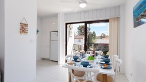 A dining area with a table set for four, a refrigerator, and a view of the outside. - Krait Court, 1 6-8 Krait Cl - great 2 bedroom unit close to little beach (Nelson Bay)