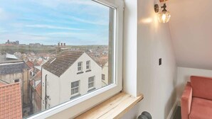Una habitación con un ventanal grande que da a un paisaje urbano, un estante de madera y un radiador.