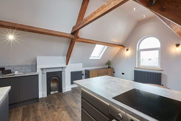 A modern kitchen with a fireplace, skylight, and wooden beams.