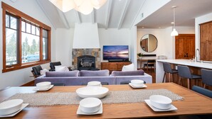 Una sala de estar moderna con chimenea, un comedor con platos blancos y una cocina con armarios de madera.
