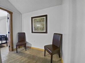 A room with two wooden chairs, a framed picture on the wall, and a carpeted floor.