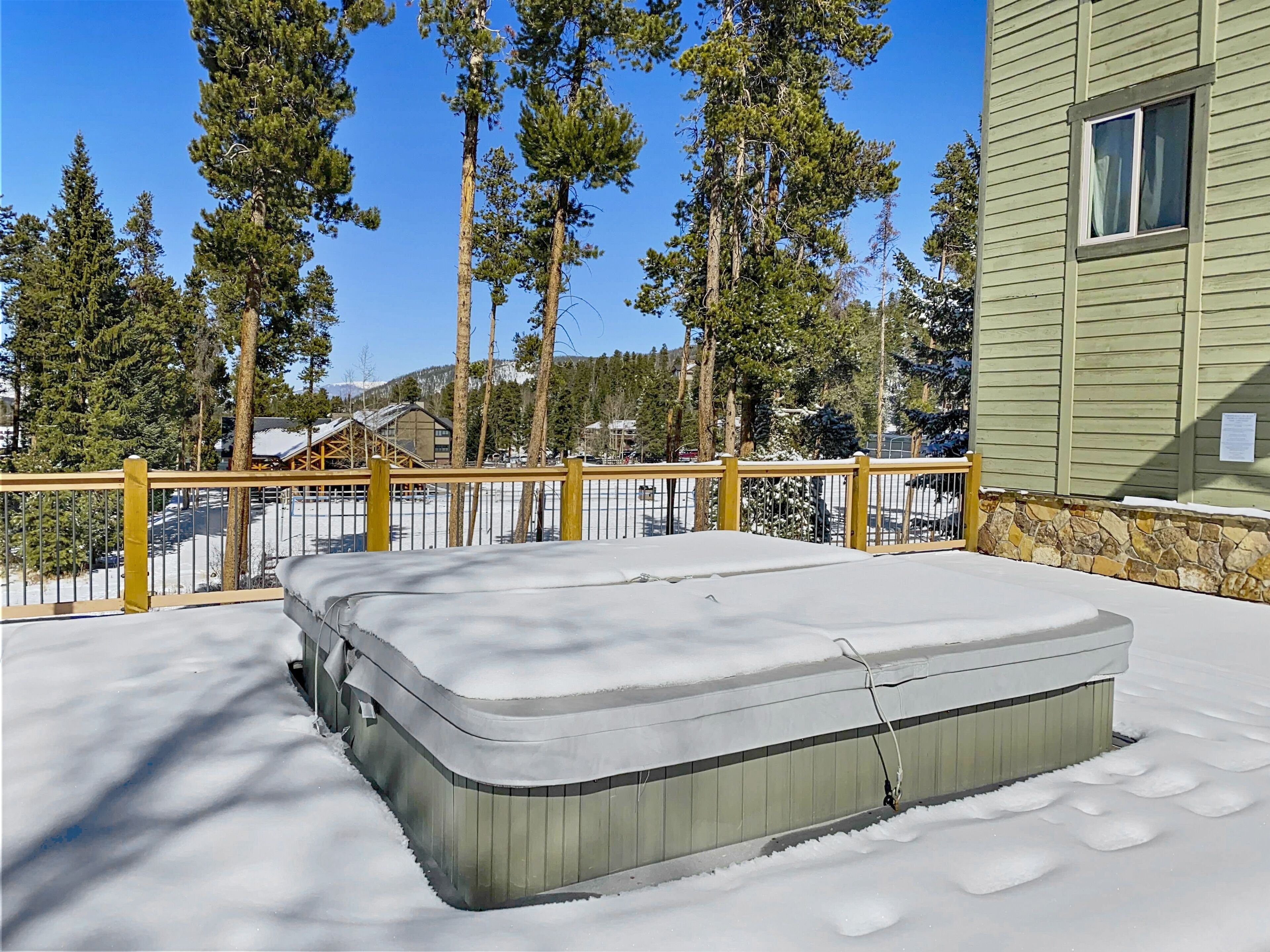 A snow-covered outdoor area with a wooden deck and a mattress on the ground.
