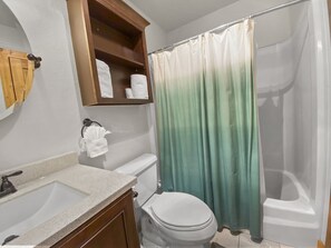 A bathroom with a white sink, a toilet, a shower curtain, and a wooden shelf with towels. - Powder Ridge 209 4 Bedroom Condo by RedAwning (Breckenridge)