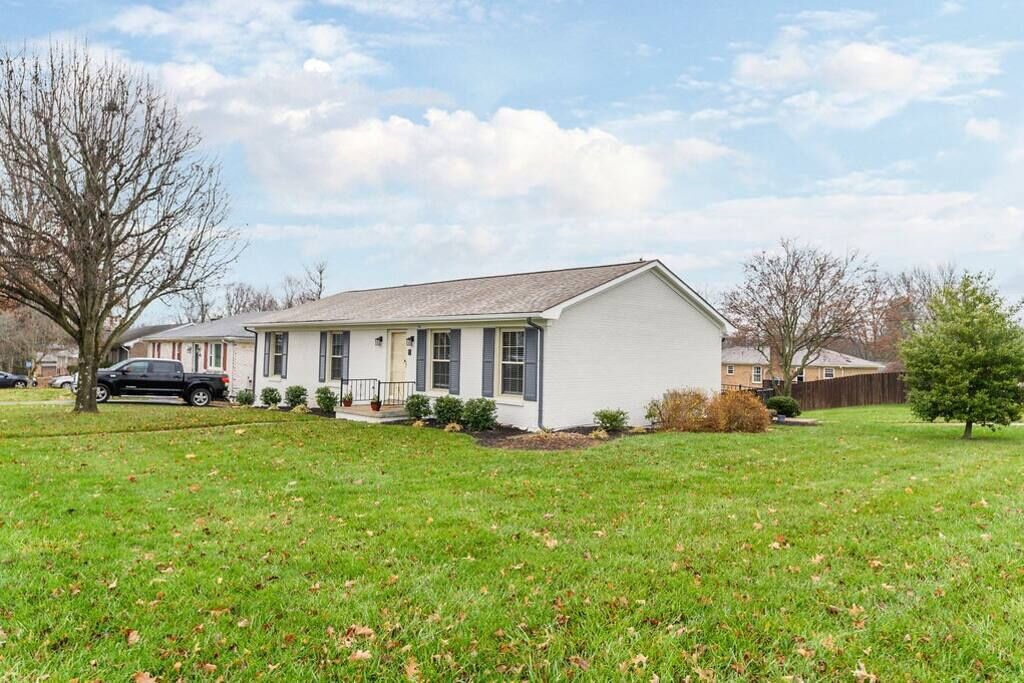 A single-story house with a front porch, a lawn, and a tree in the yard.