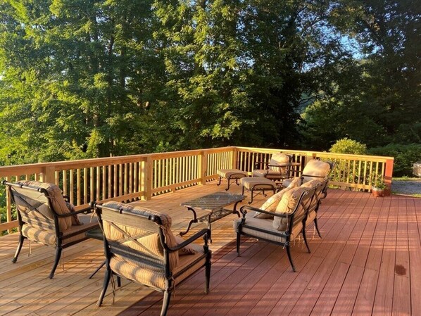 A wooden deck with outdoor furniture, including sofas and a table, surrounded by trees. - Ascendere - Amazing mountain views, 3 bedroom, 2 bath, central heat/AC, private. (Maggie Valley)