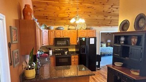 A kitchen with wooden cabinets, a microwave, a refrigerator, and a bar area with stools. - Ascendere - Amazing mountain views, 3 bedroom, 2 bath, central heat/AC, private. (Maggie Valley)