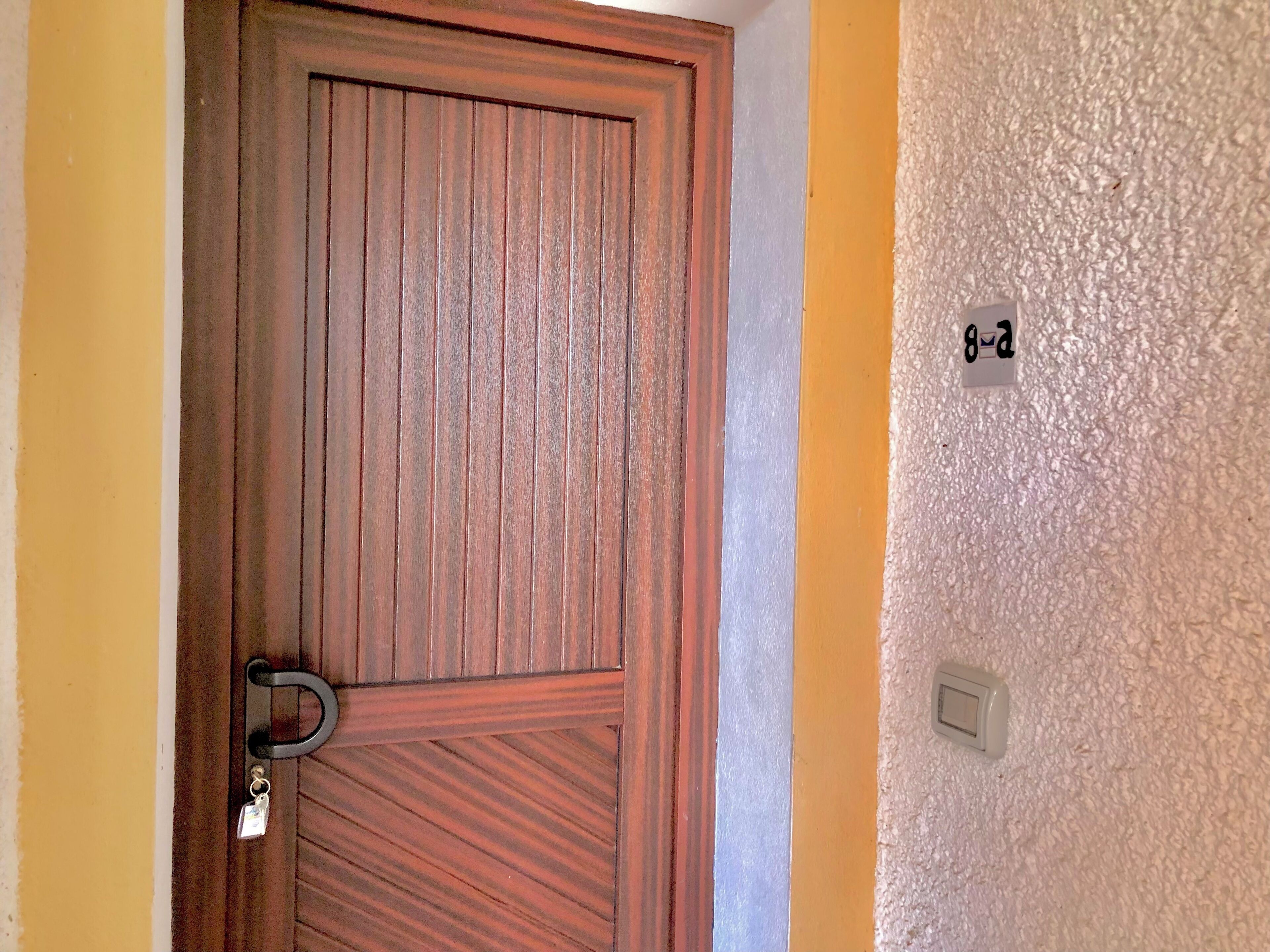 A wooden door with a keyhole and a doorbell.