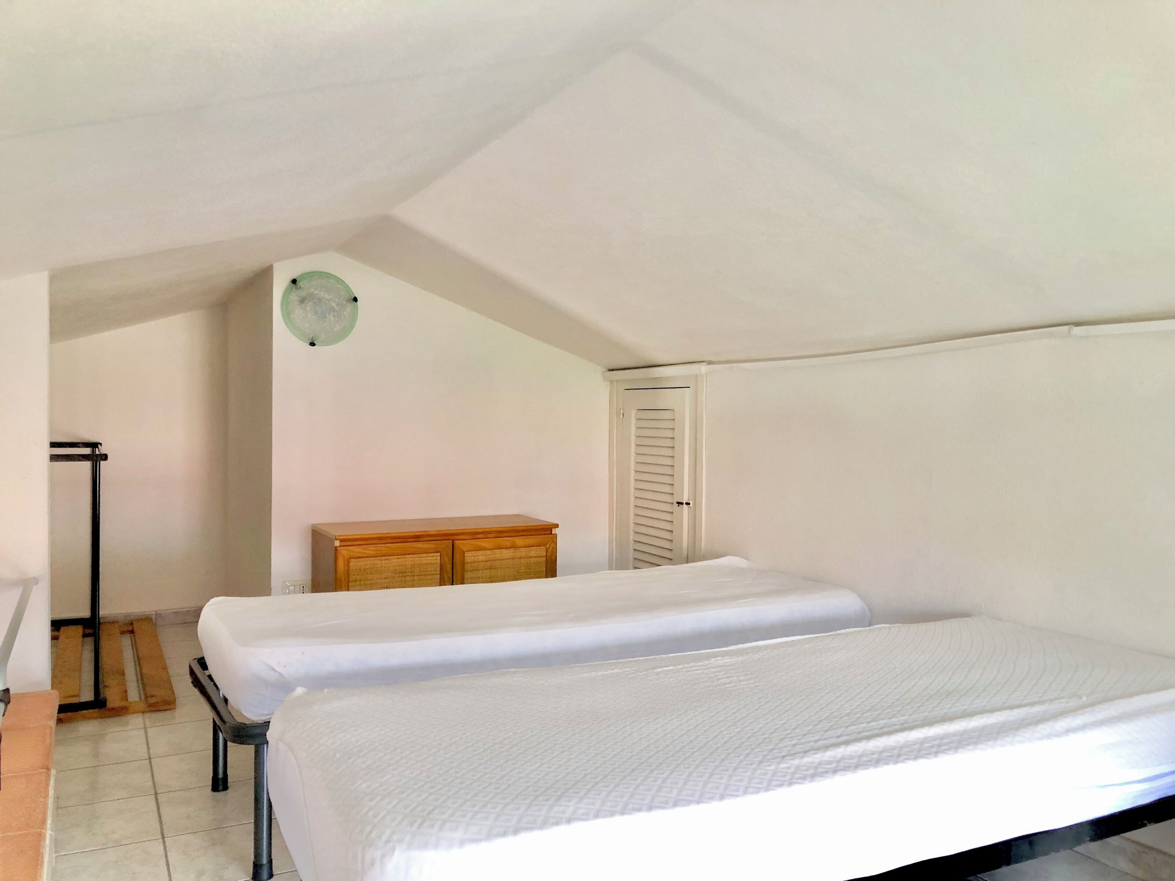 Una habitación con dos camas, un aparador de madera, una puerta y un radiador.