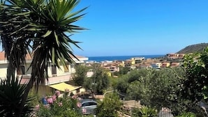 A residential area with a view of the sea, stone steps, and a parked car. - Residence L'Ancora (Castelsardo)
